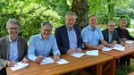 Sechs Männer unterzeichnen an einem Tisch den Vertrag zum Internetportal waldwissen