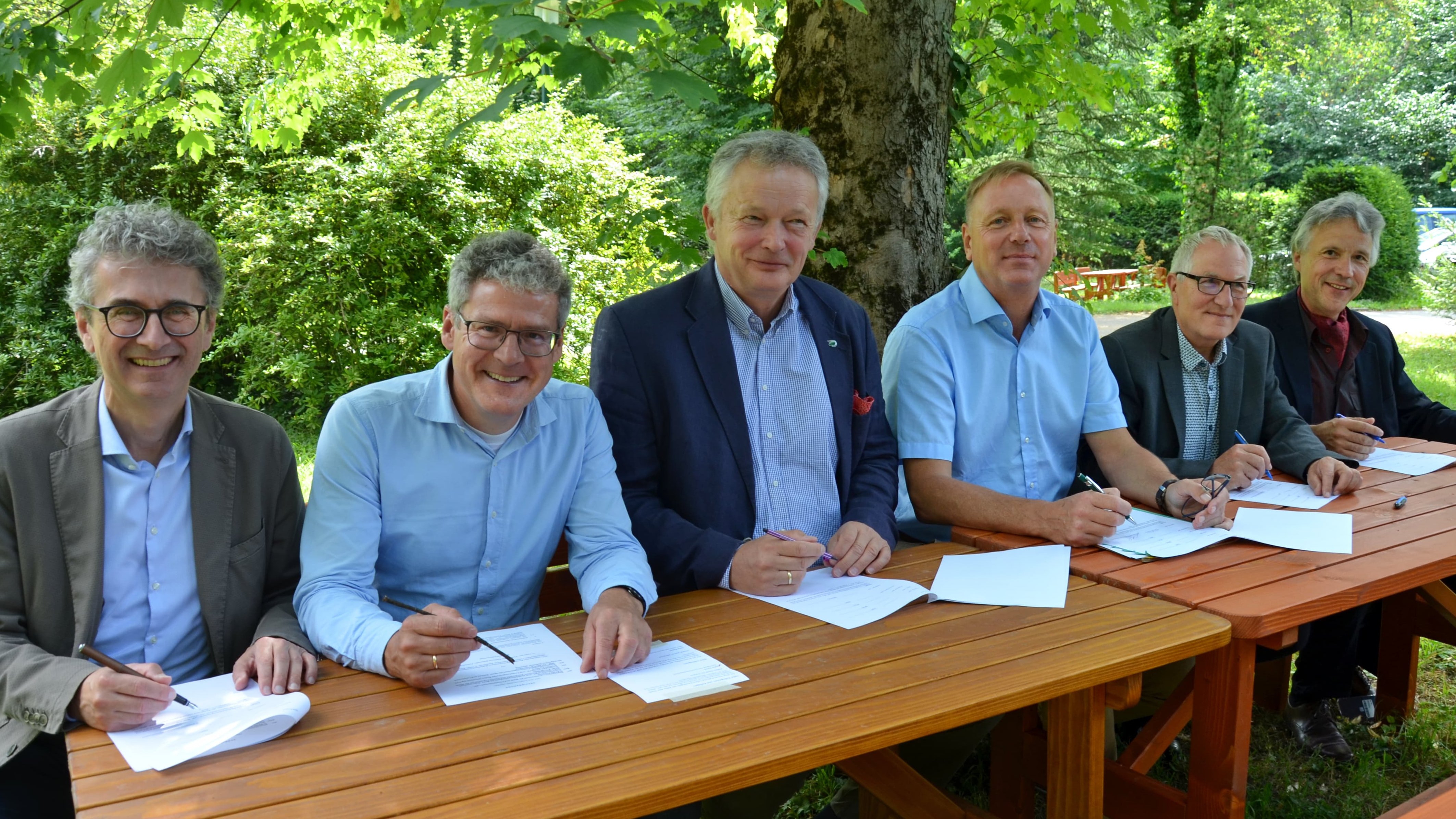 Sechs Männer unterzeichnen an einem Tisch den Vertrag zum Internetportal waldwissen