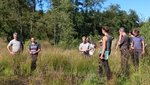 Personen, die in einem Waldmoor einem Vortrag zuhören.