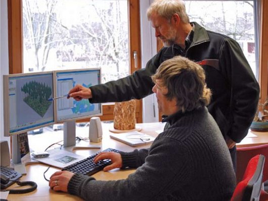Zwei Mitarbeiter diskutieren Simulation eines Waldbestandes am Computerbildschirm