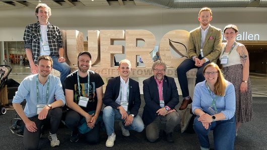 Vor großformatigen Holz-Buchstaben IUFRO sind die acht Tagungsteilnehmenden der NW-FVA zu sehen.