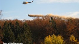Hubschrauber verteilt Kalk über einem Wald