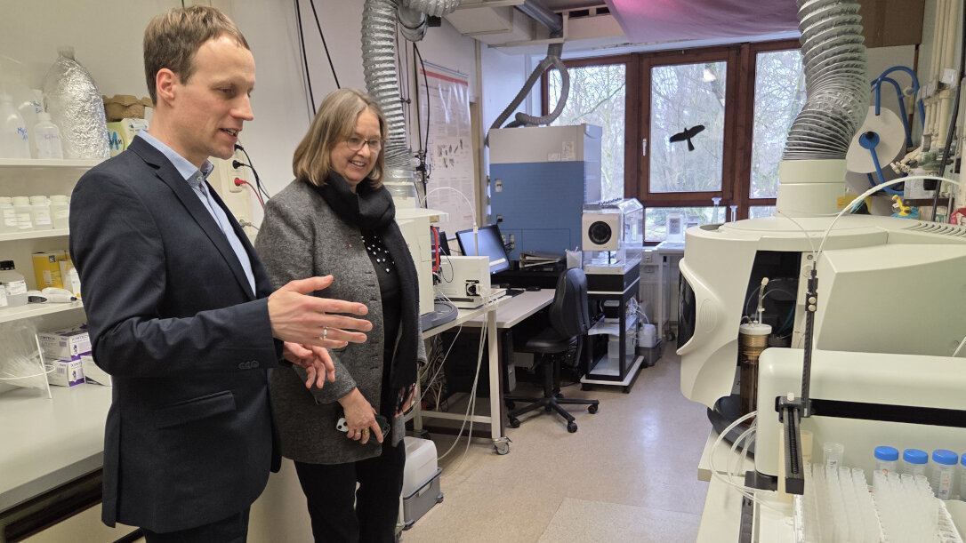 Laborleiter Alpermann erklärt Staatssekretärin Patzke ein wissenschaftliches Gerät.