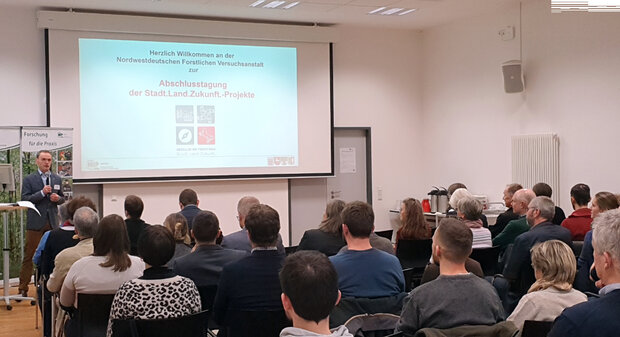 Menschen von hinten hören einem Redner zu.