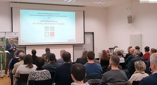 Menschen von hinten hören einem Redner zu.